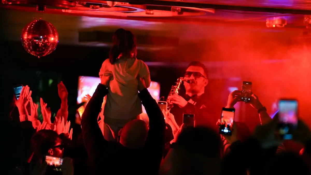 After-party crowd dancing to live saxophone under the mirror ball on the AMOR dinner cruise