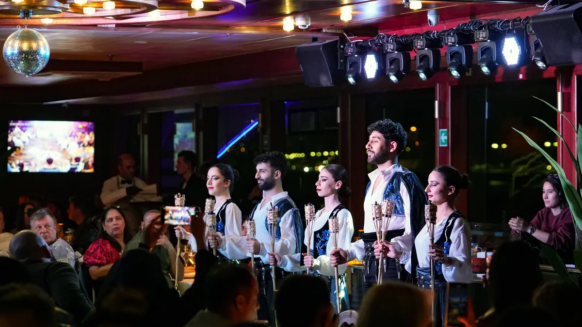 Caucasian dance troupe in traditional costumes holding torches on the dinner cruise