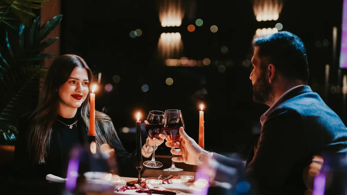 Couple toasting at a candlelit table aboard the AMOR