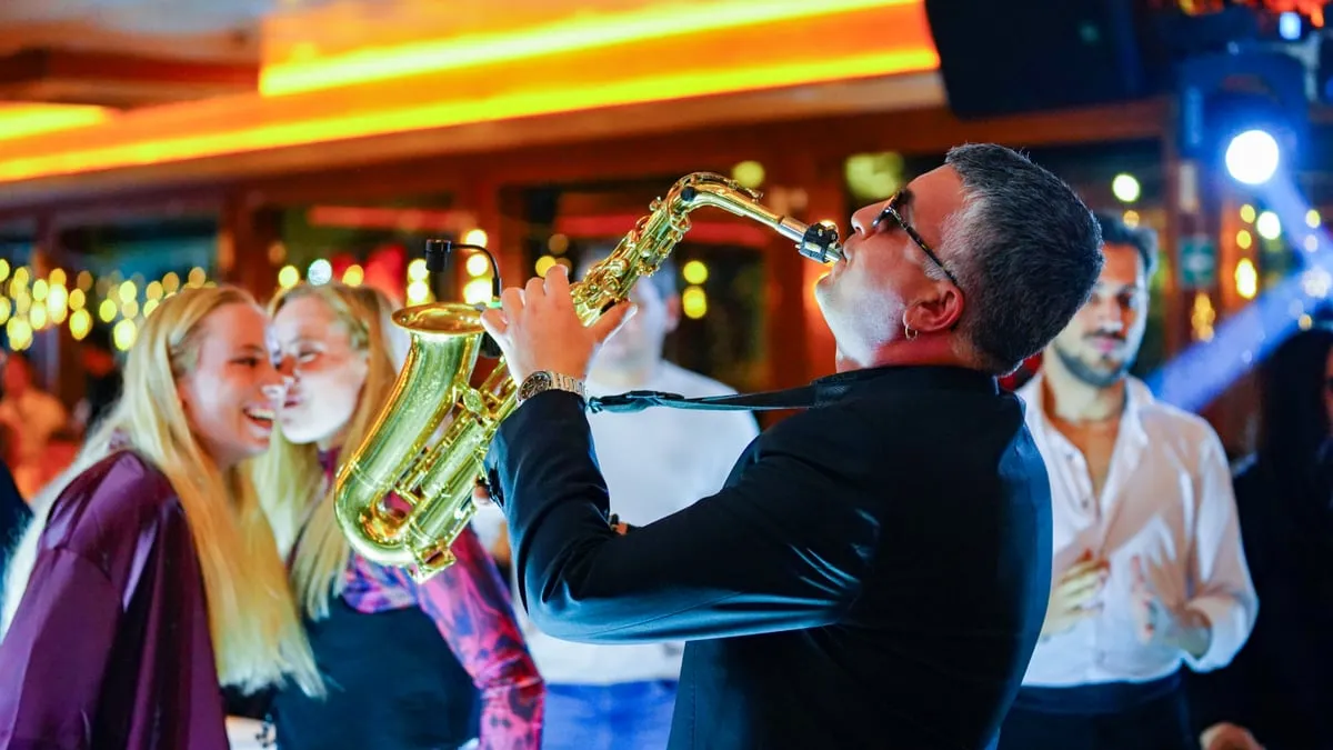 Saxophonist playing among dancing guests on the AMOR Bosphorus dinner cruise
