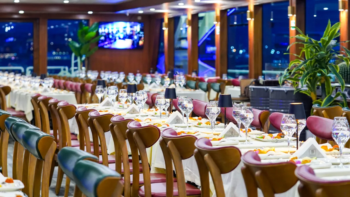 Dining hall with velvet seating and crystal glassware aboard the AMOR