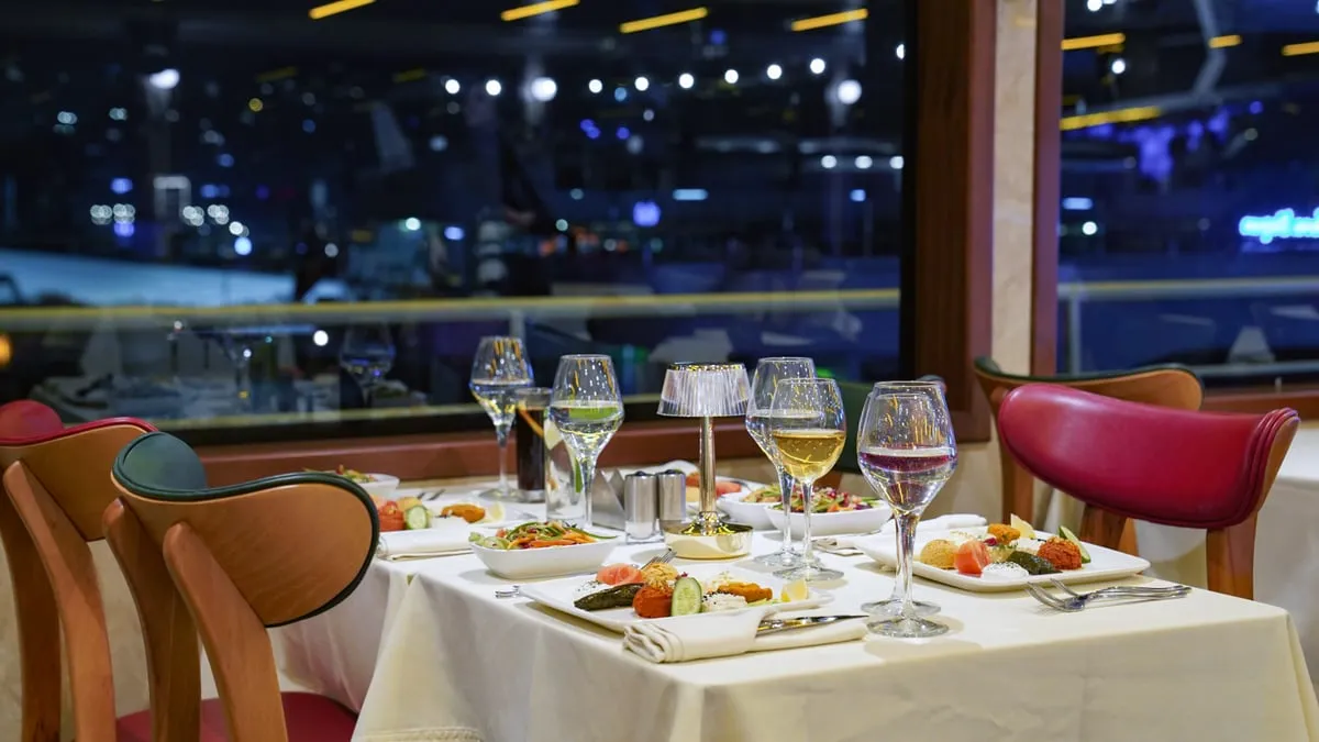 Window table set for dinner with the illuminated Bosphorus shoreline behind on the AMOR
